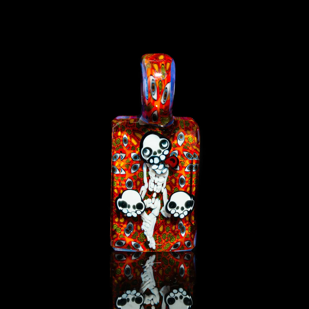 Colorful heady glass pendant with skull and bones design on vibrant red background