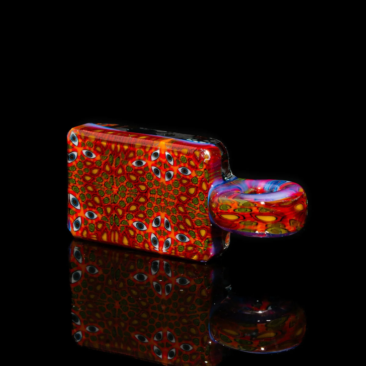 Vibrant rectangular glass hand pipe with psychedelic eye pattern on black background
