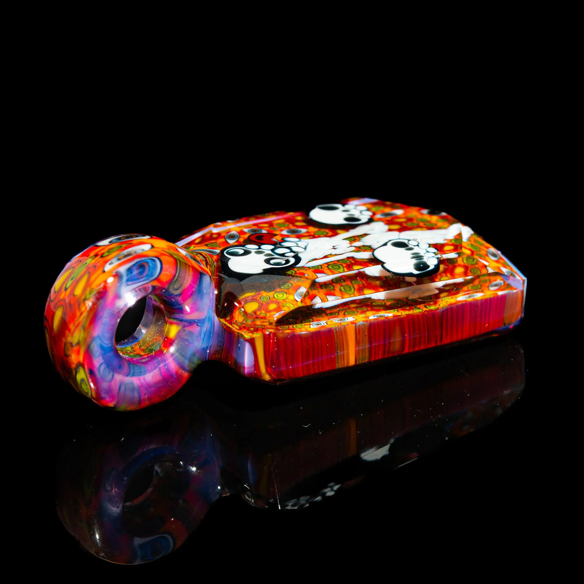 Colorful glass hand pipe with panda designs on vibrant orange and red background, black backdrop
