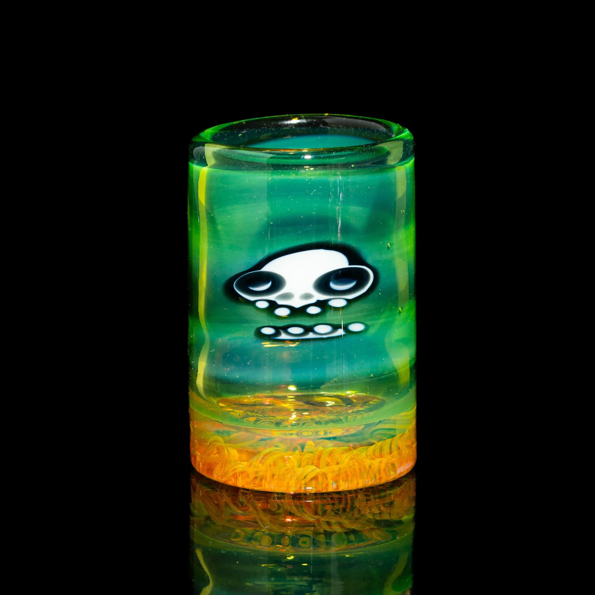 Colorful glass accessory with skull design, green and yellow, on a black background