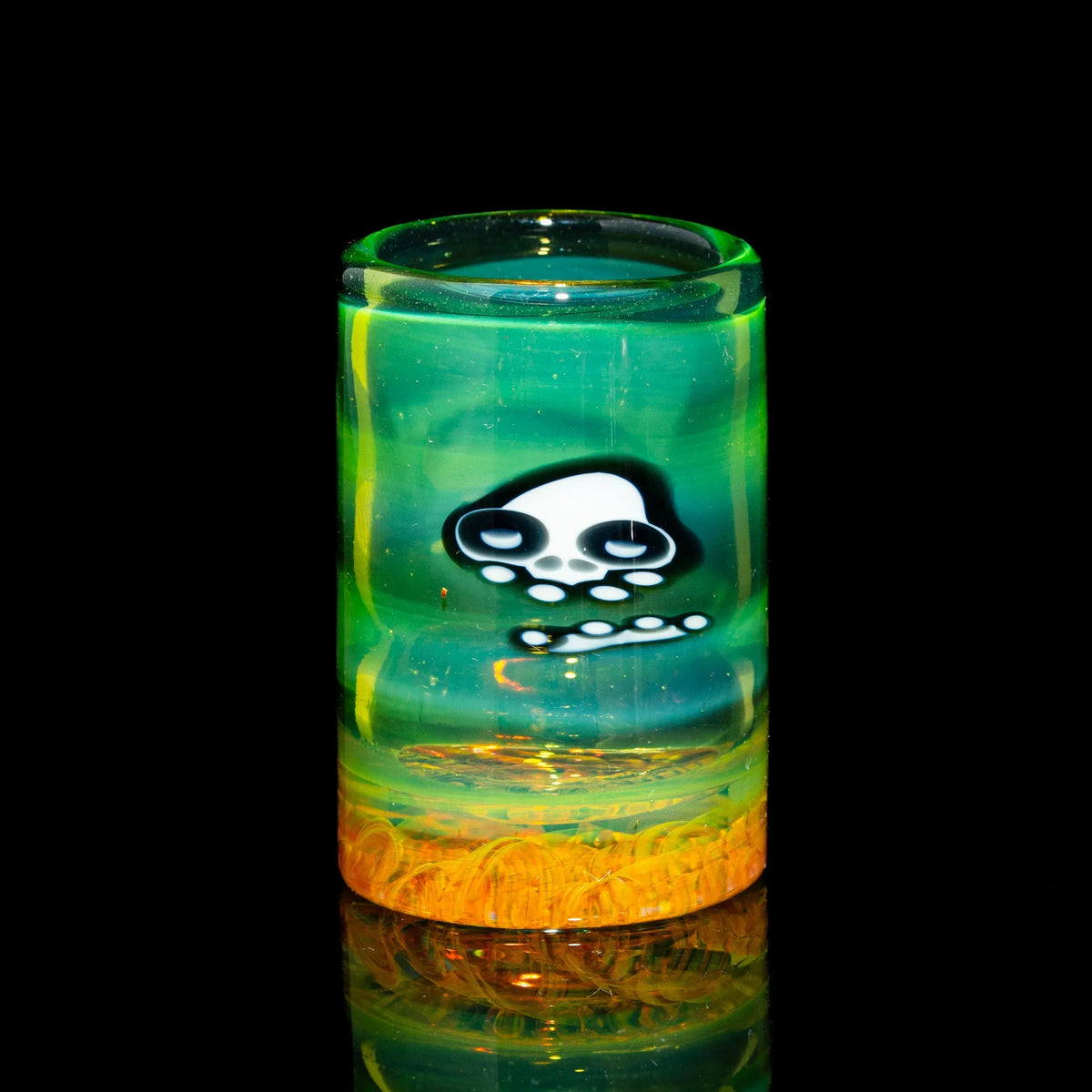 Handblown glass slide with green and yellow tones, featuring a cartoon skull design