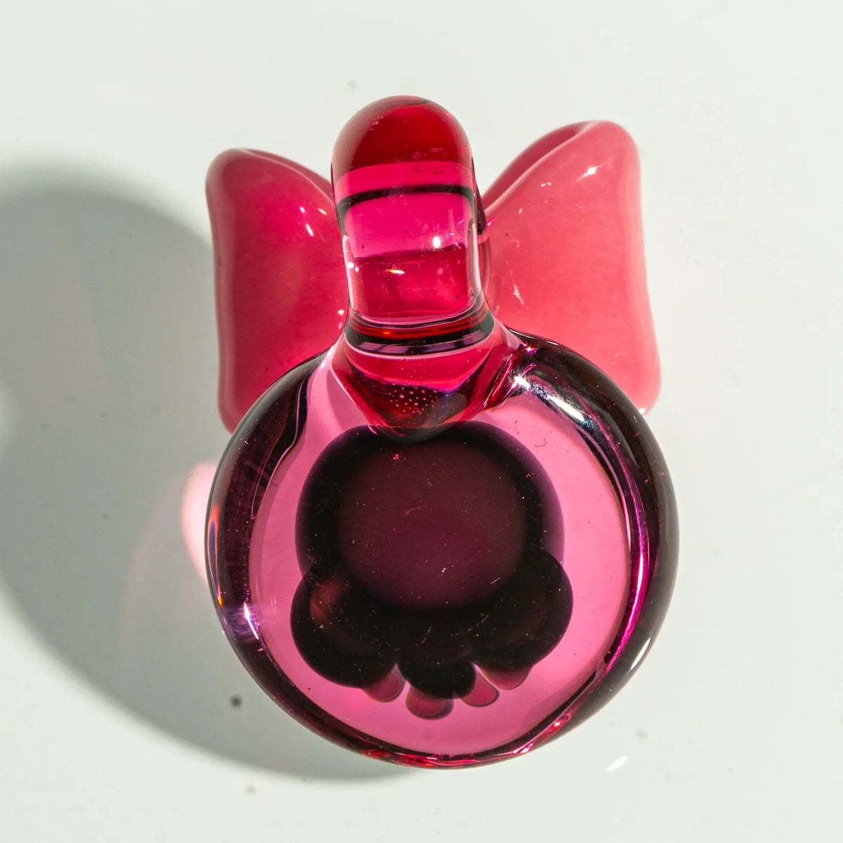 Pink glass carb cap with sculpted bow, used for dab rigs and smoking accessories