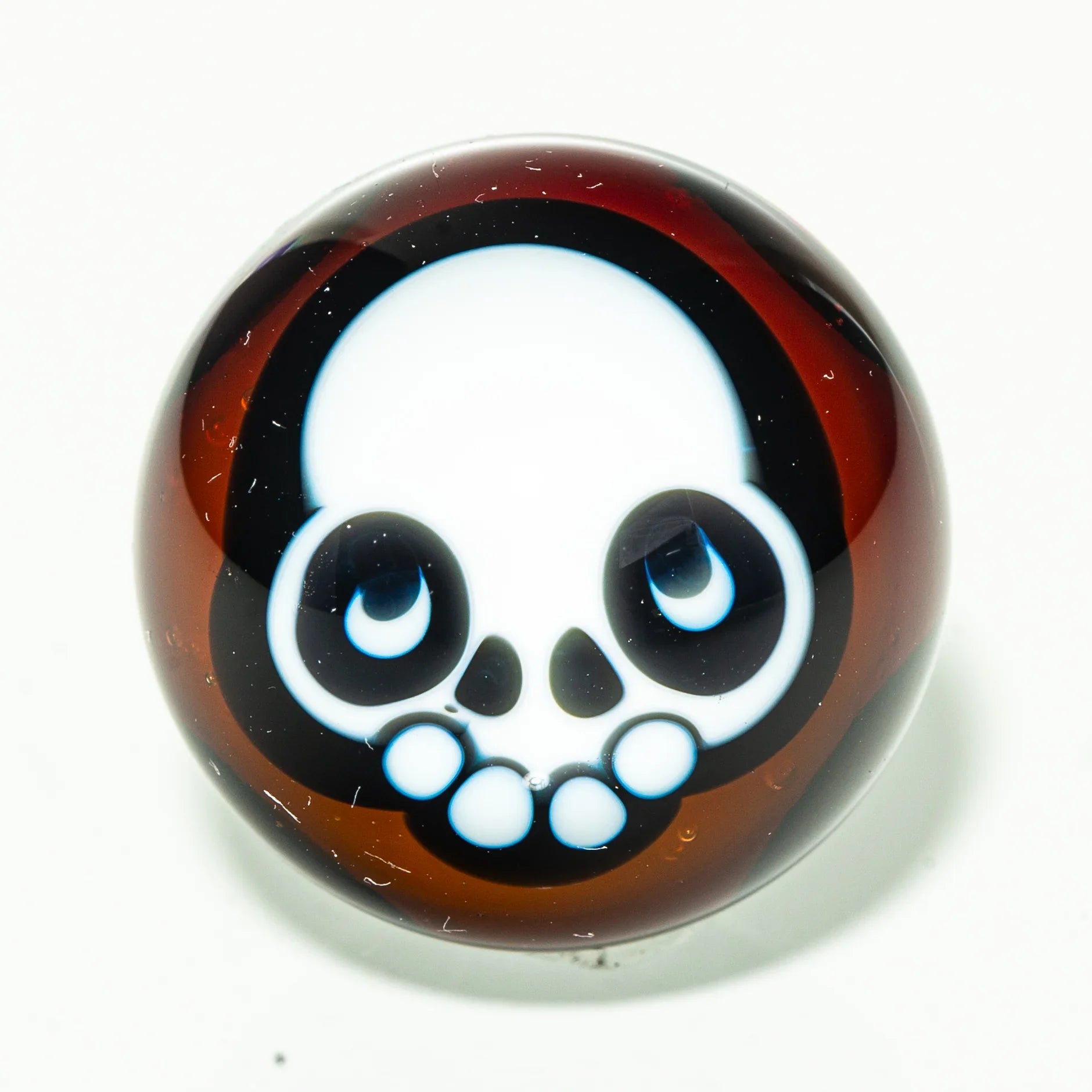 Brown glass marble with cartoon skull design, heady glass accessory on white background