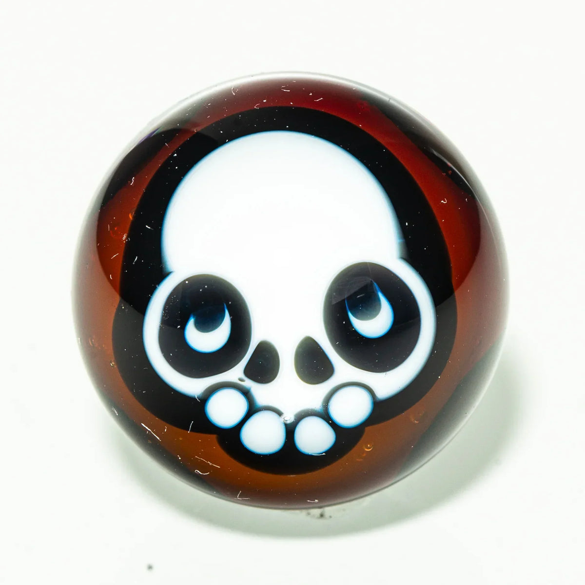 Brown glass marble with cartoon skull design, heady glass accessory on white background