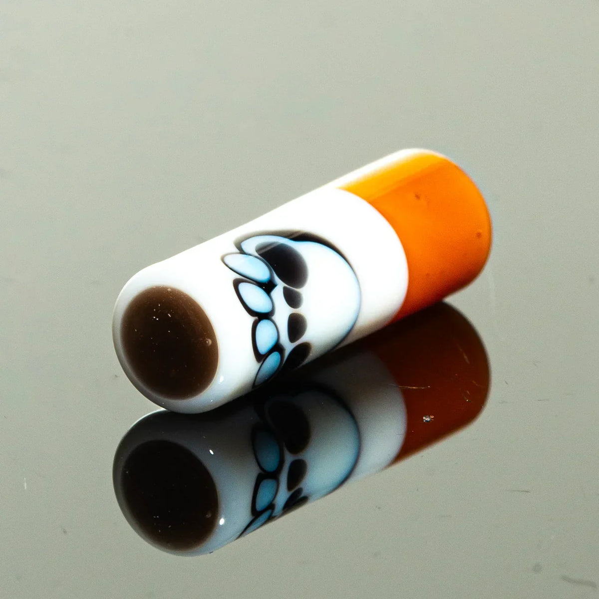 Glass chillum with orange tip and blue bear paw design on reflective surface