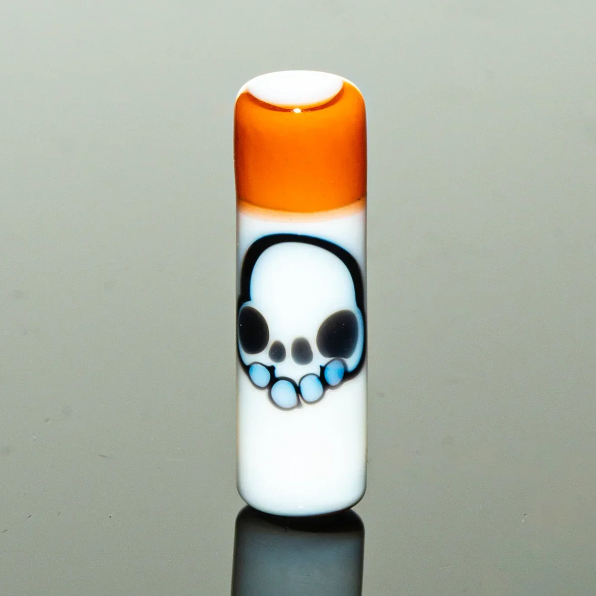White glass accessory with orange top and blue skull design, reflective surface