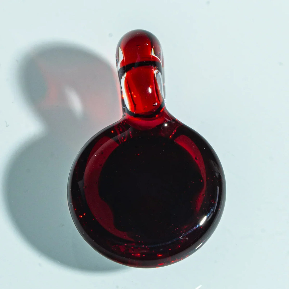 Red glass pendant carb cap with a loop handle on a white background