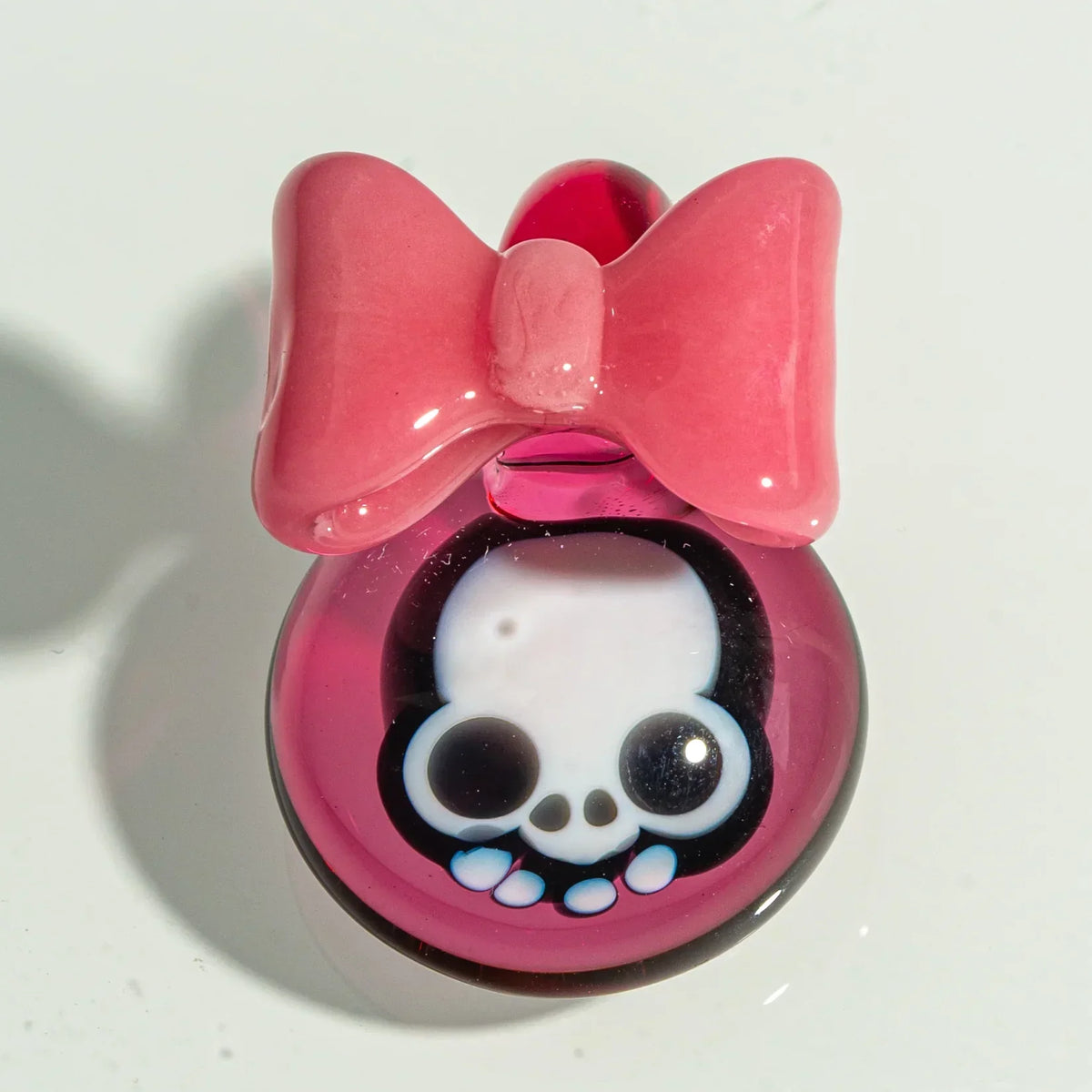 Pink glass pendant with a white skull design and a large pink bow, cute smoking accessory