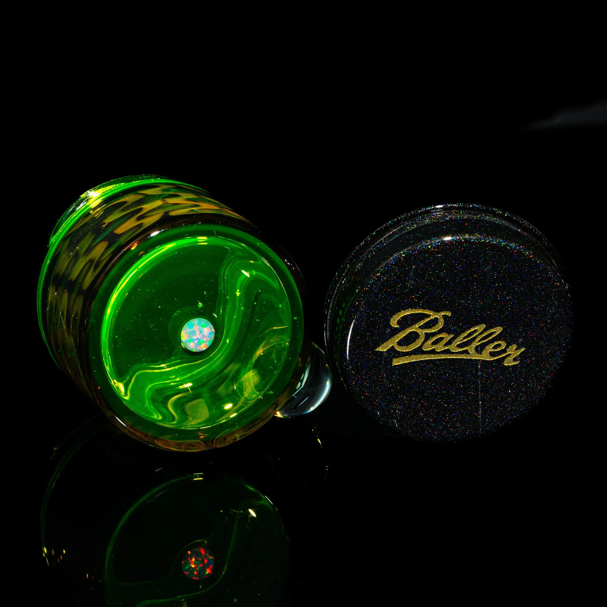 Green glass stash jar with opal detail and a glittery lid labeled 'Baller' on black background.