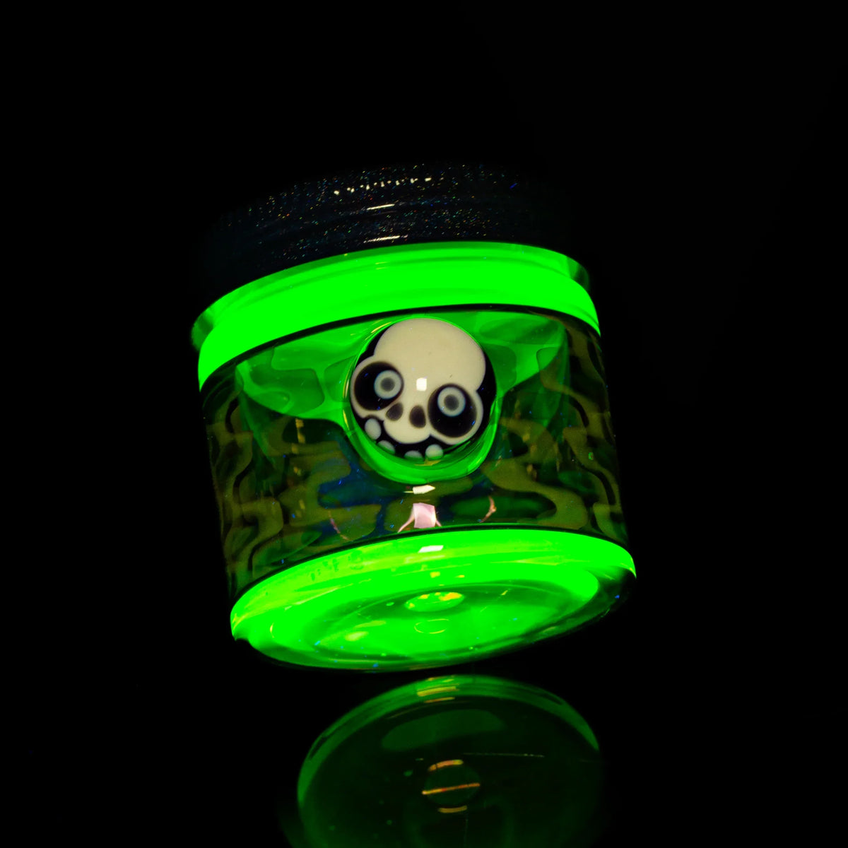 Glow-in-the-dark glass jar with skull detail, heady glass accessory on black background