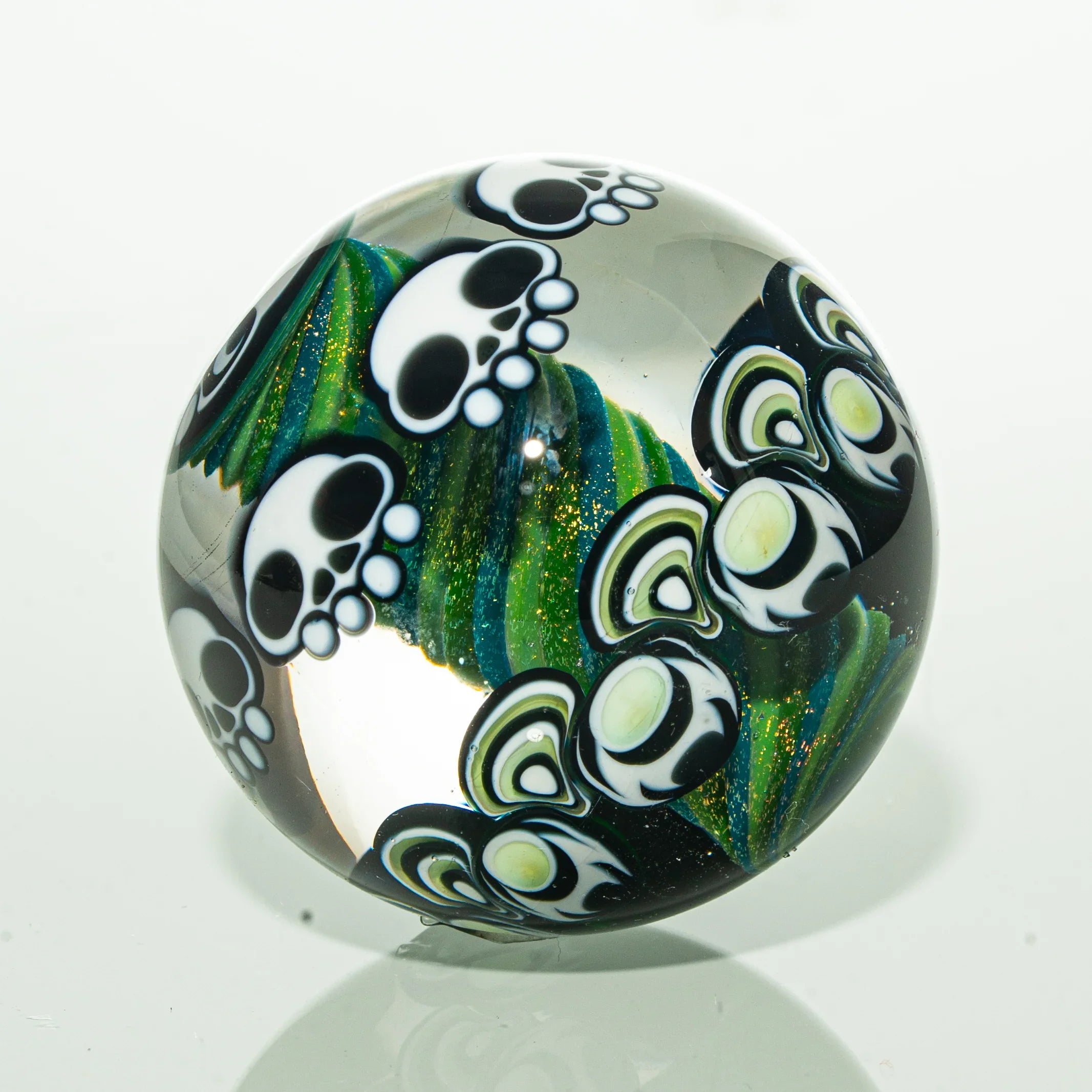Hand-blown glass marble with skull and paw print designs and green spiral details