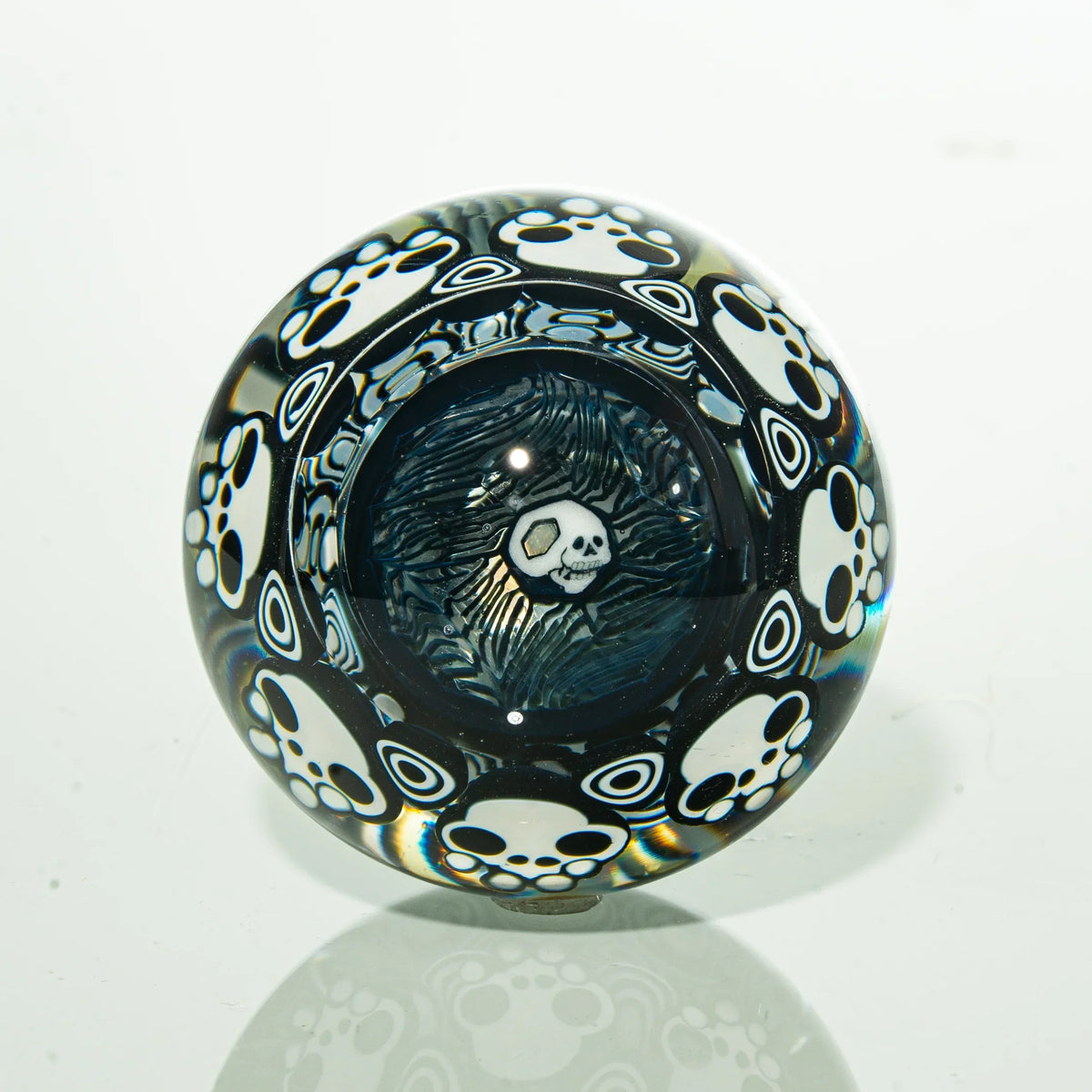 Glass marble with white skull and paw print designs on a clear background