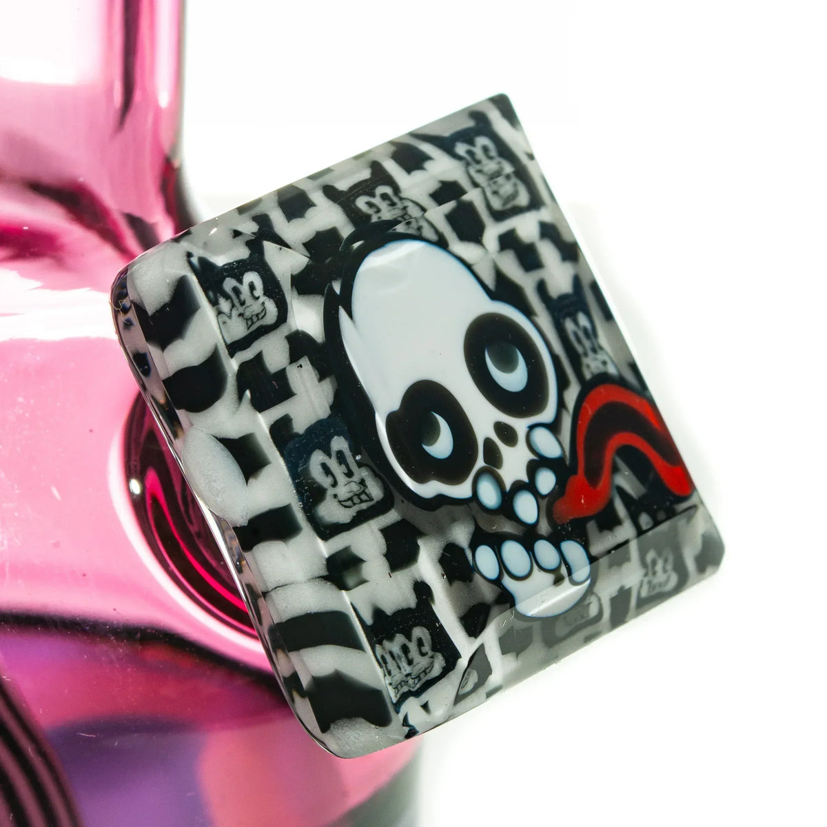 Close-up of pink glass bong with black and white skull art and cartoon face details