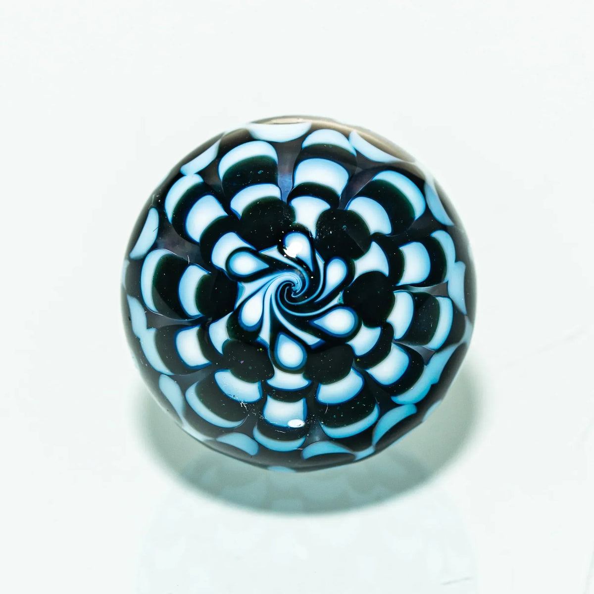 Intricate glass marble with blue and white spiral pattern, heady glass art accessory