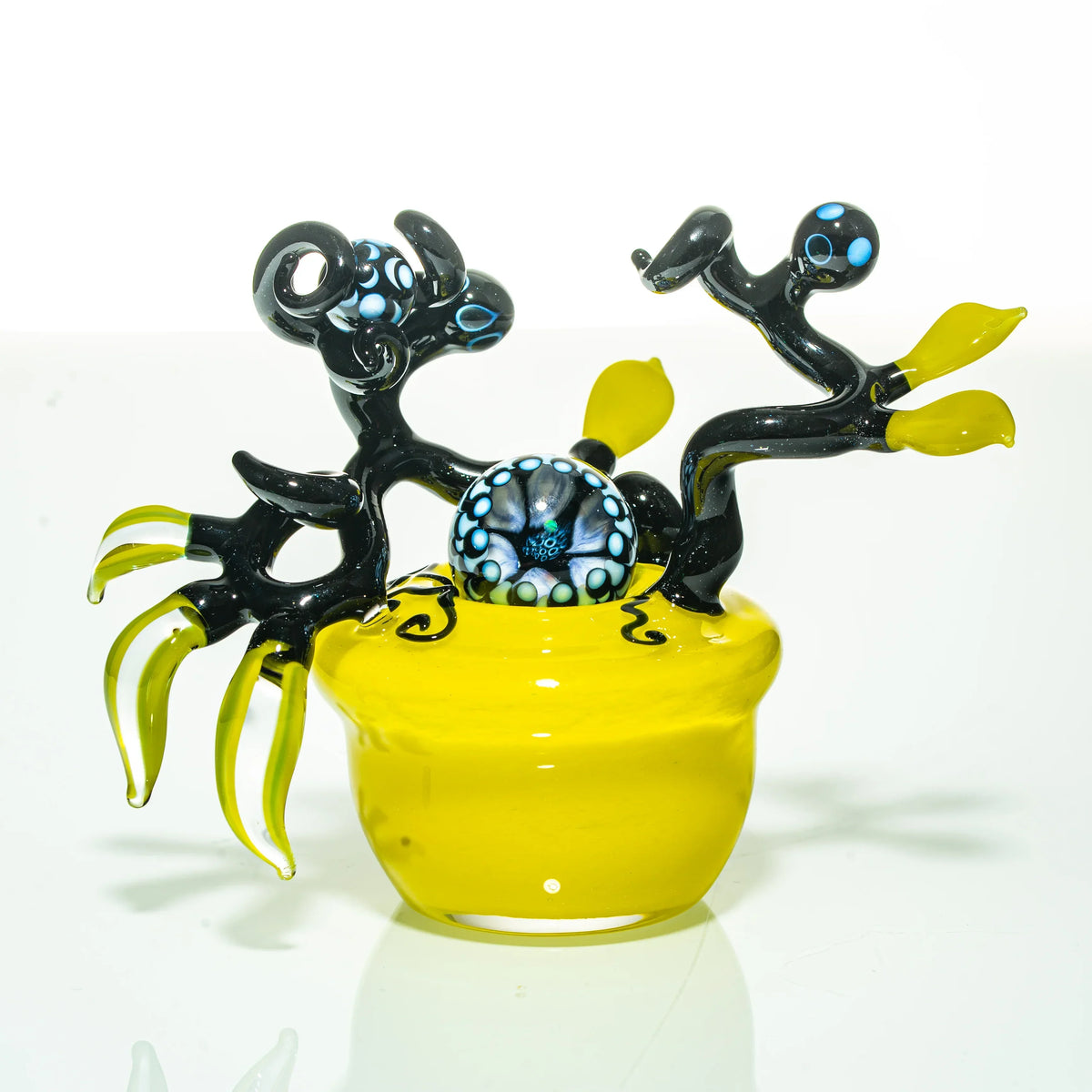 Handcrafted yellow and black glass art piece with intricate sculpted figures and marble accent