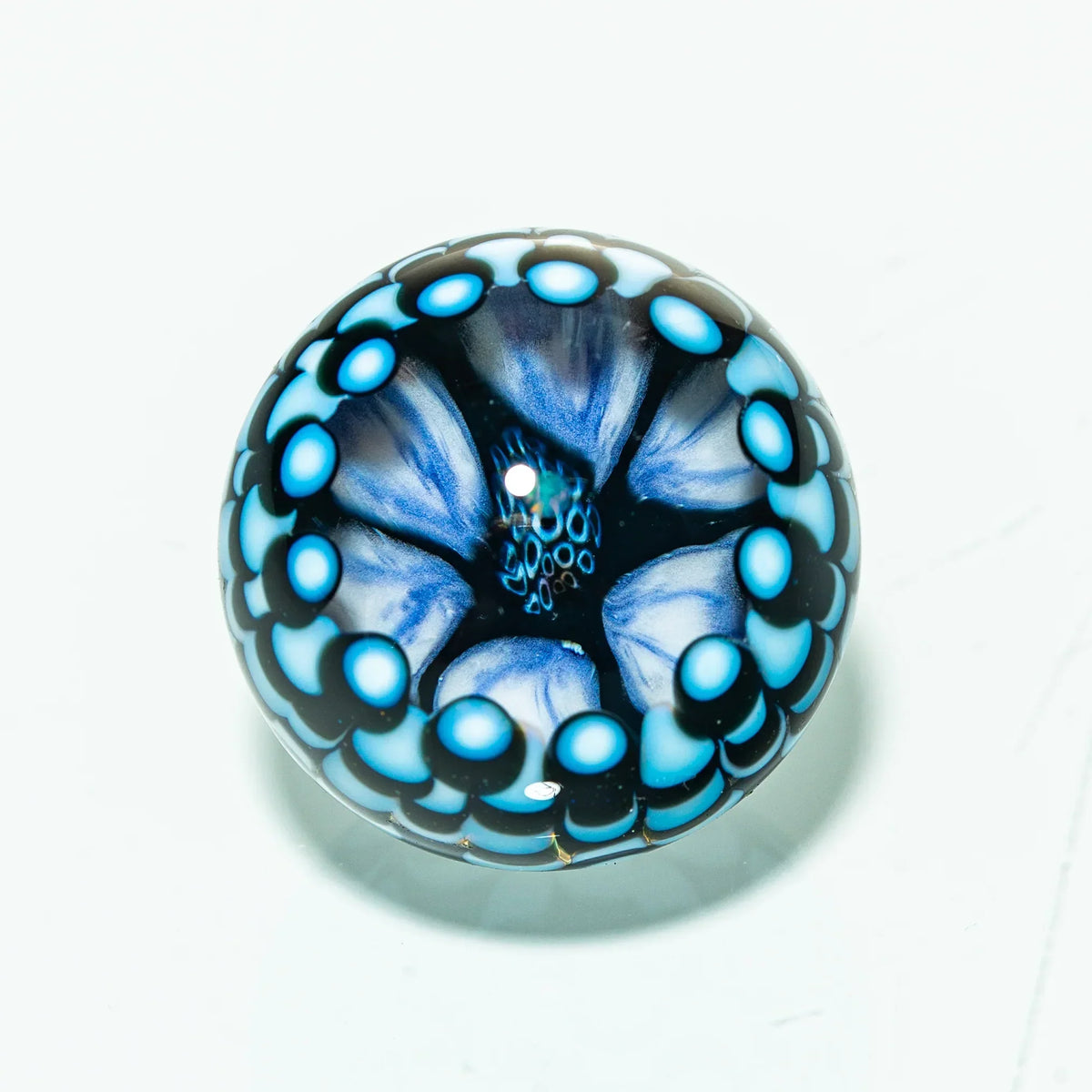 Blue and black heady glass marble with intricate flower design on white background
