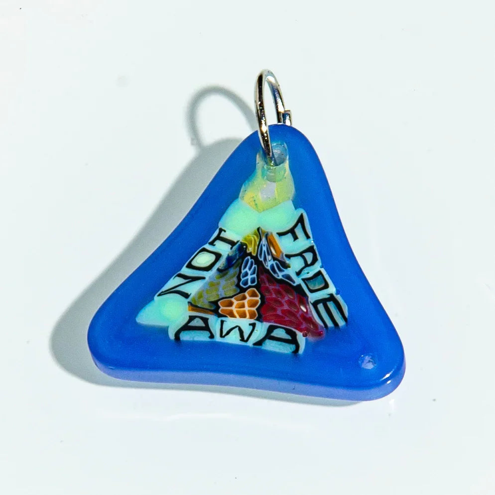 Blue triangular glass keychain with colorful design and text reading 'Not Fade Away'.