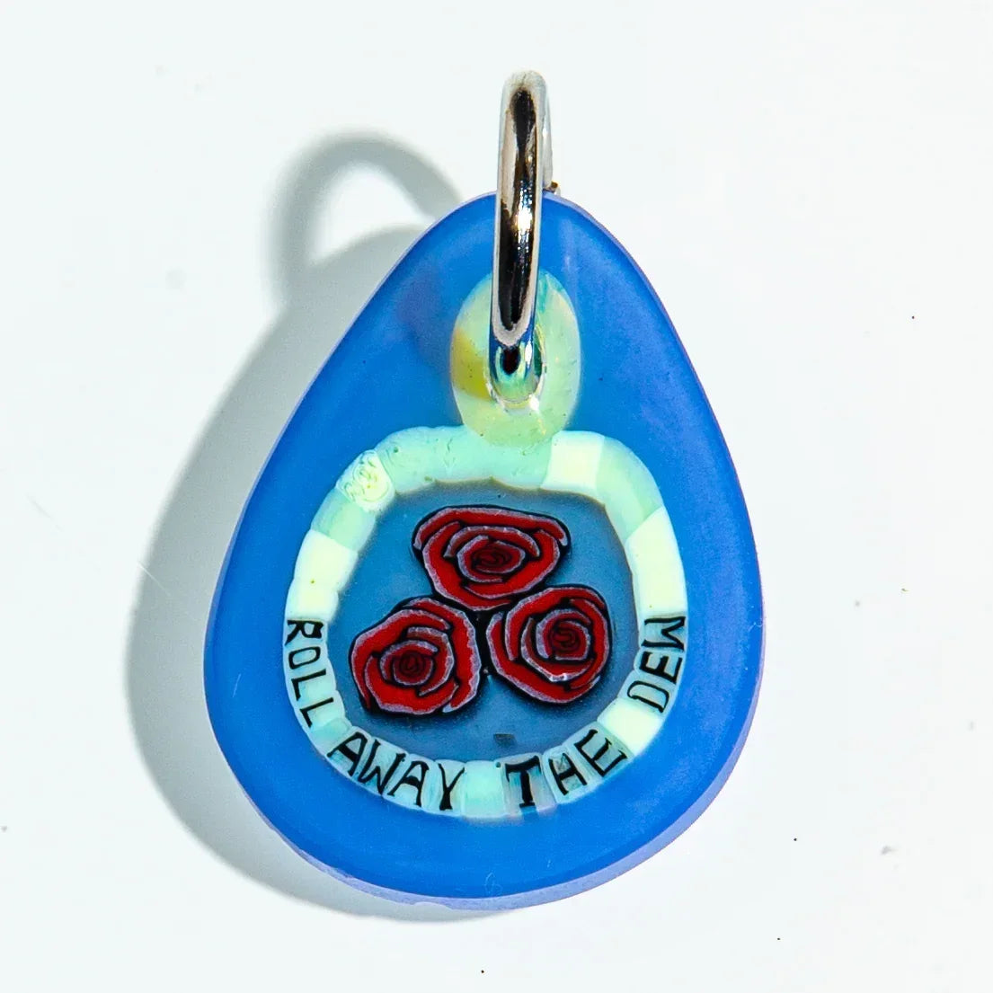 Blue glass keychain with red rose designs and 'Roll Away The Dew' text, on white background