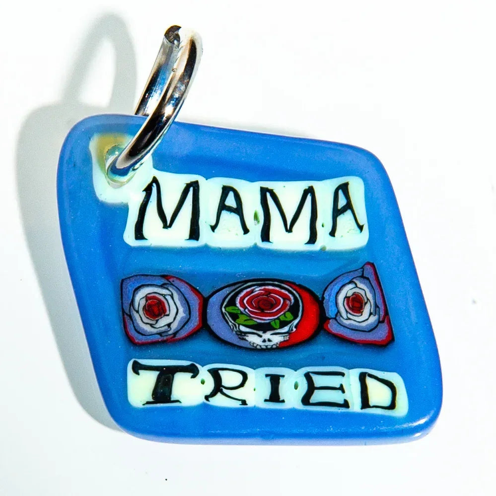 Blue glass keychain with 'Mama Tried' text and rose skull design, on white background