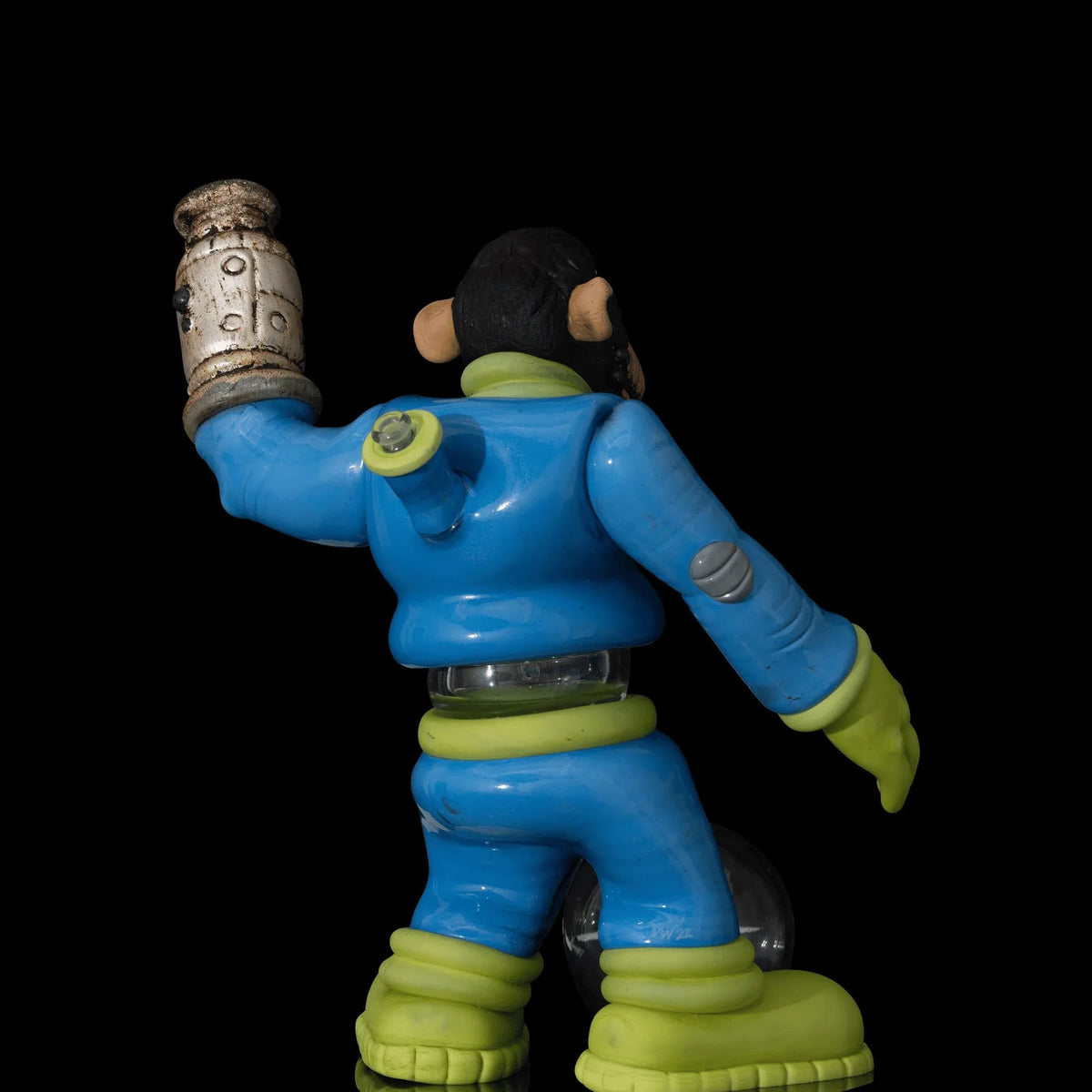 Colorful glass art monkey figure in blue and green suit, holding detailed piece, black background
