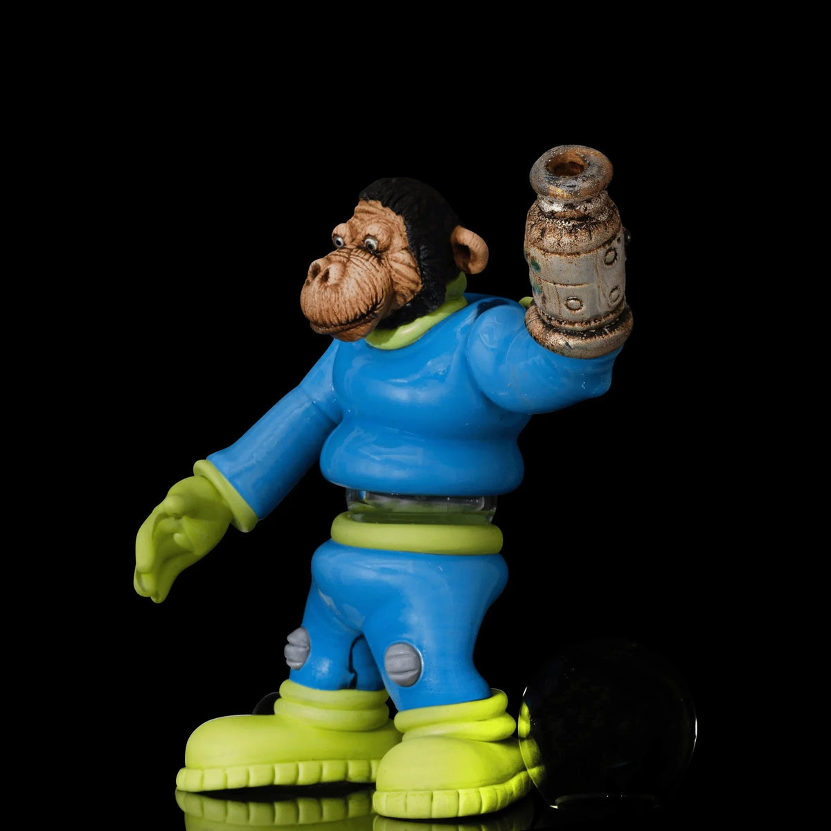 Art glass monkey figure in blue and green suit, holding a sculpted accessory, black background