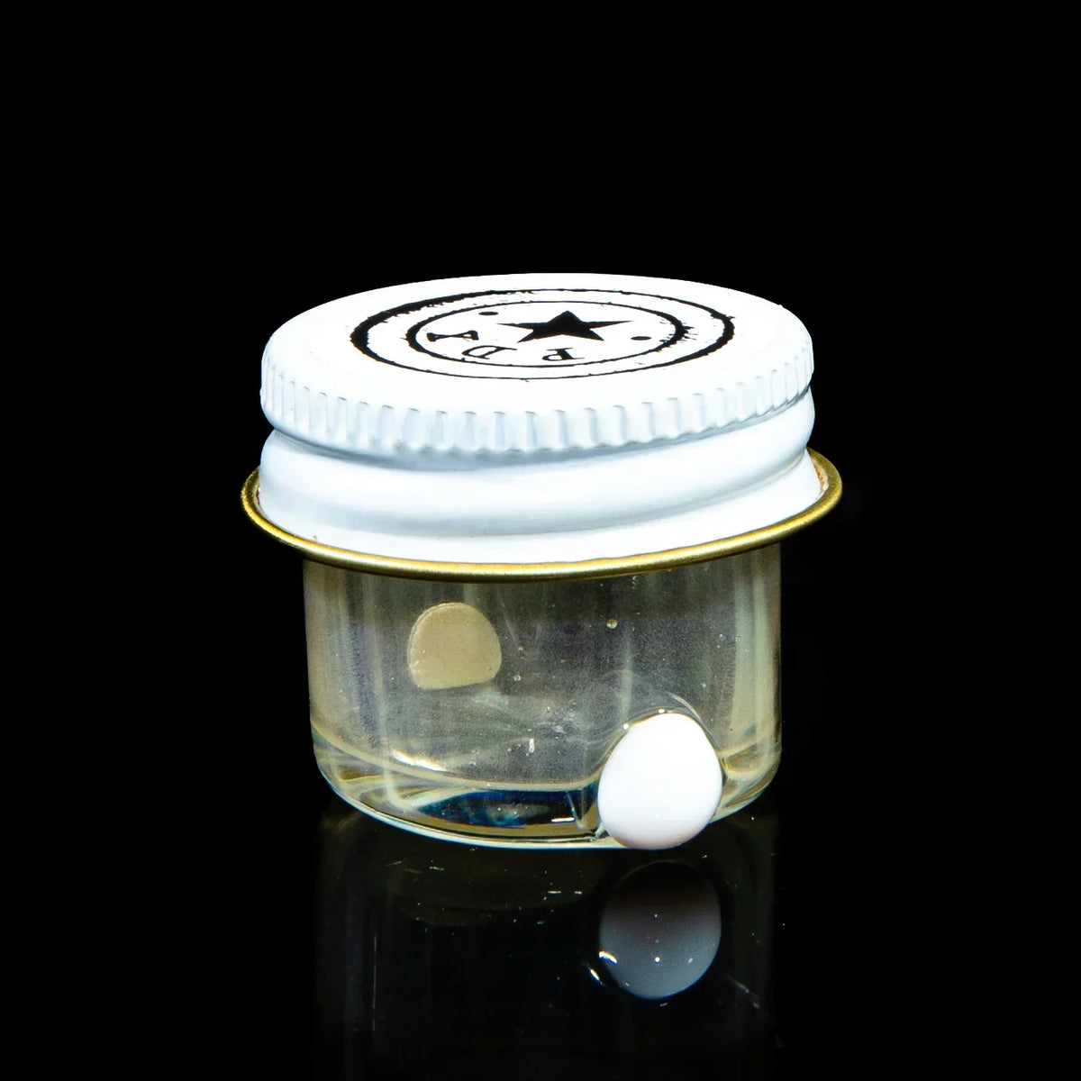 Small clear glass concentrate jar with white lid and black logo, shown on black background