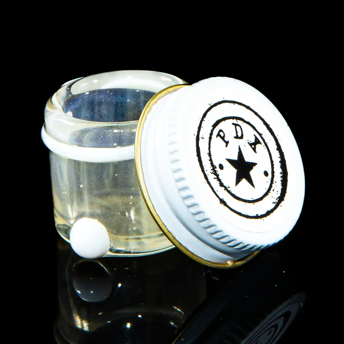 Clear glass storage jar with white lid and black star logo, shown open on black background