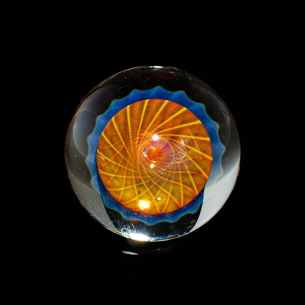 Handblown glass marble with orange and blue spiral design on black background