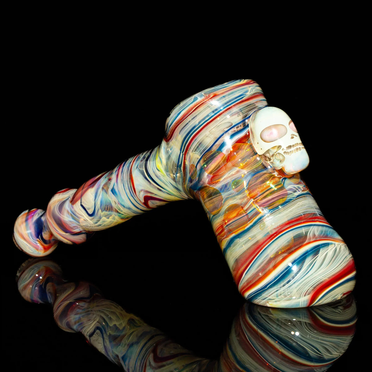 Colorful heady glass hammer pipe with a skull detail, displayed on a black background