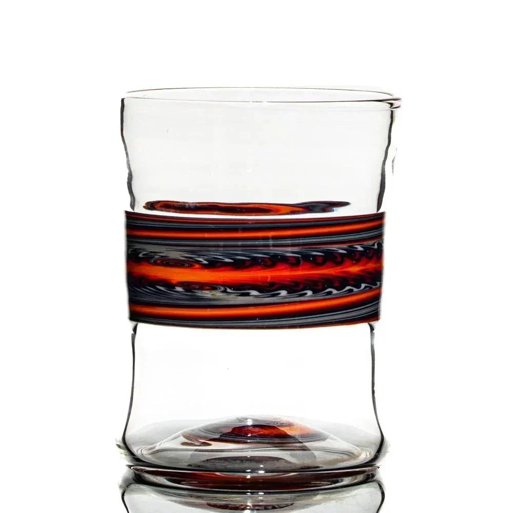 Handblown glass tumbler with a red and black swirl accent band, clear background.