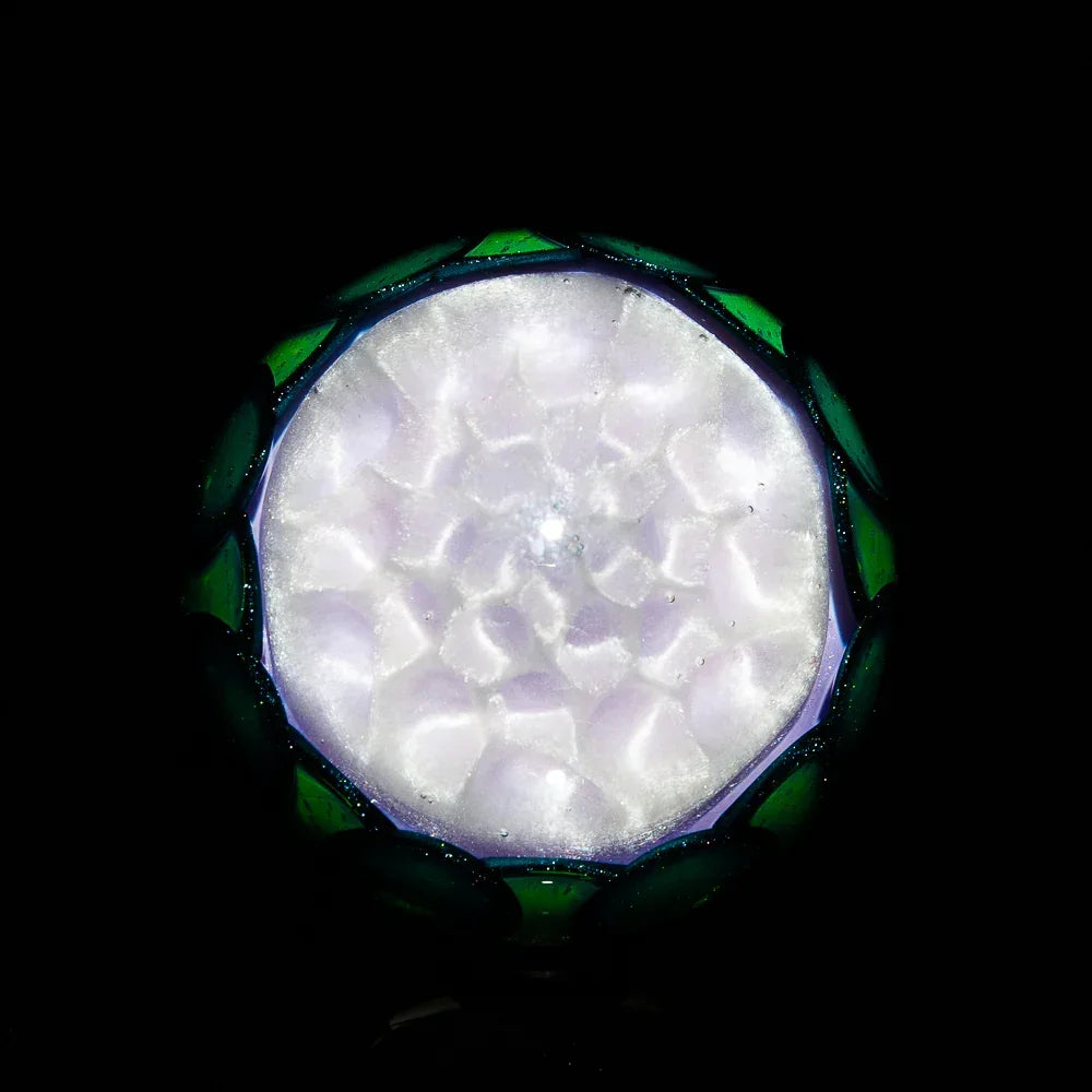 Intricate glass art marble with frosted white pattern and green accents on black background