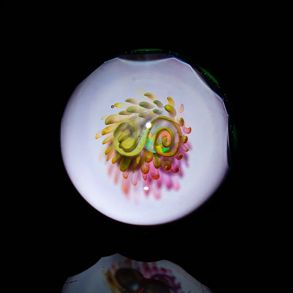 Handmade glass marble with intricate swirling flower design on black background