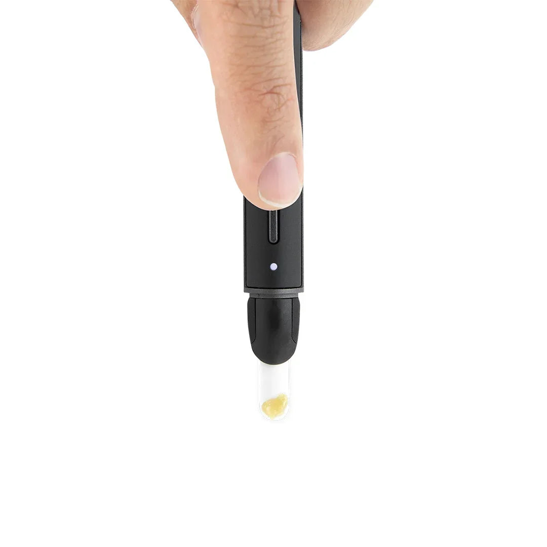 Hand holding a black electronic hot knife with glass tip for dab concentrate