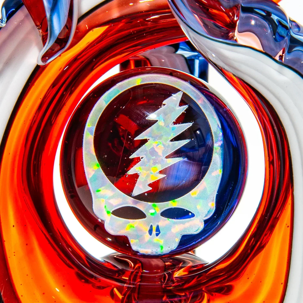 Colorful glass art with opal skull and lightning bolt medallion, red and blue swirls