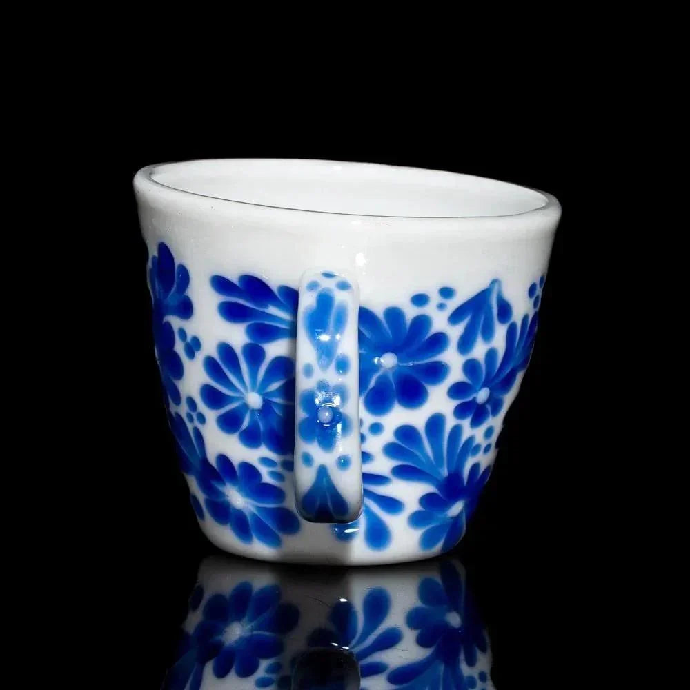 White and blue ceramic mug with floral pattern on a black background