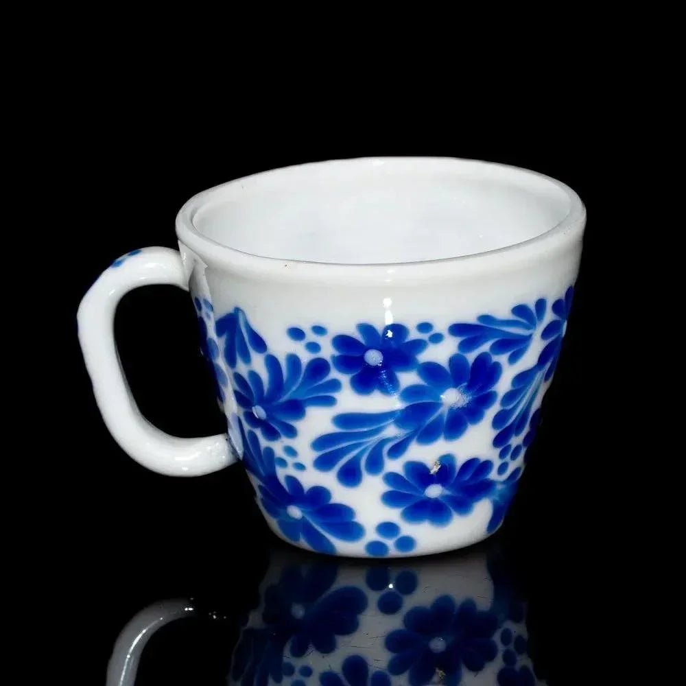 White ceramic mug with blue floral pattern on a black background
