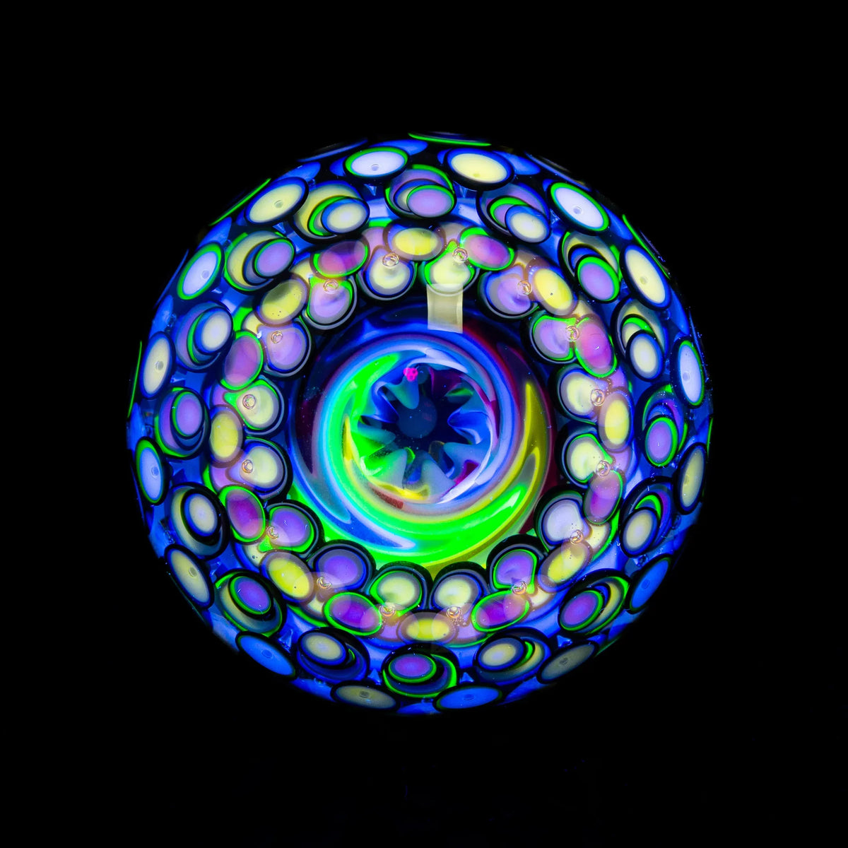 Colorful heady glass art marble with intricate UV reactive patterns on a black background