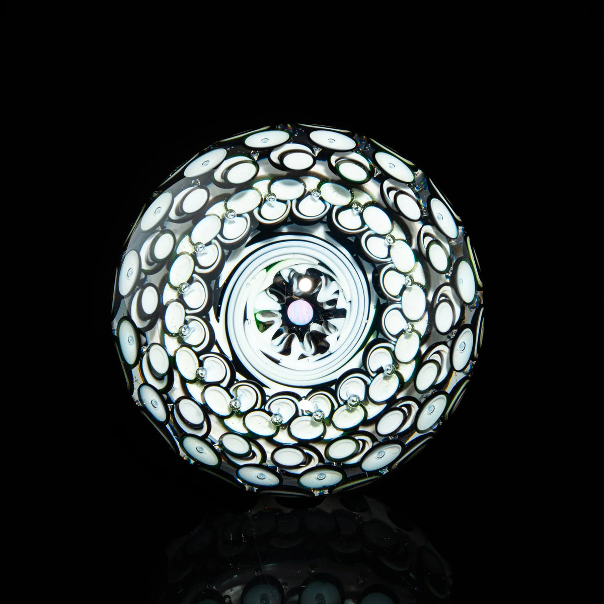 Handcrafted glass marble with intricate white and black swirling patterns on black background