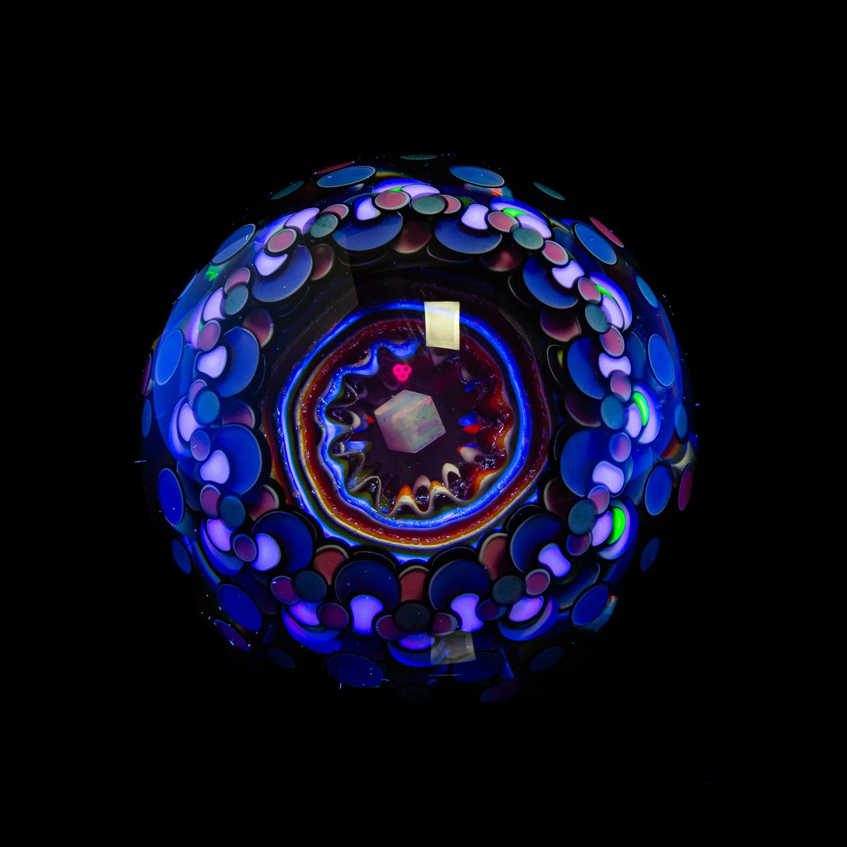 Colorful heady glass marble with intricate UV-reactive patterns on a black background