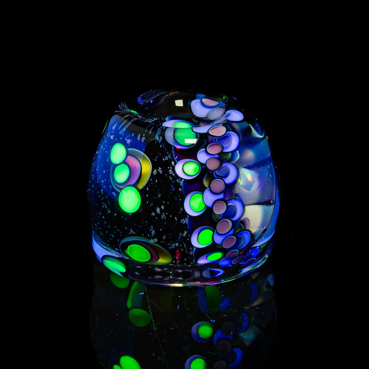 Handmade glass art marble with neon green and purple abstract patterns on black background