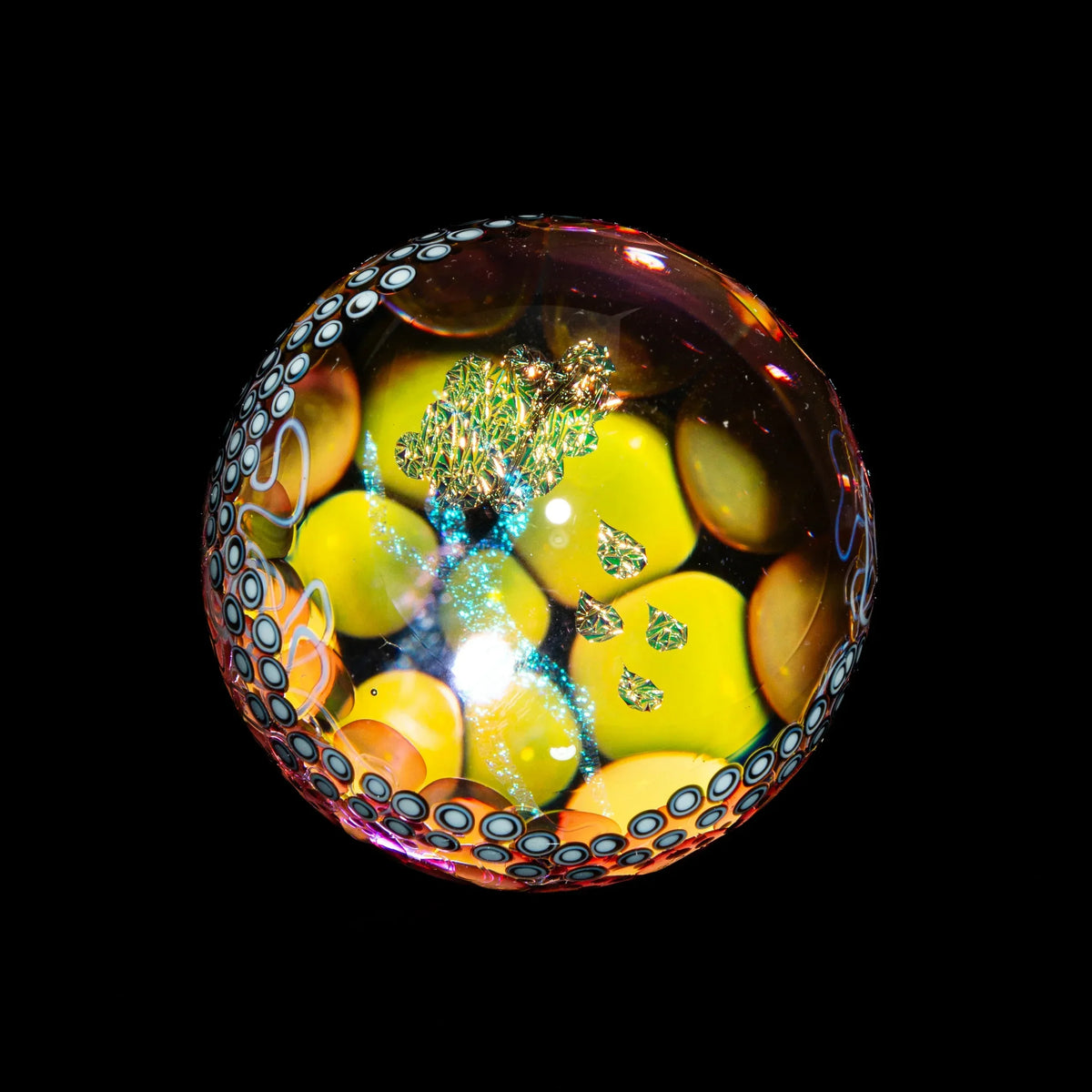 Hand-blown glass marble with psychedelic yellow, blue, and iridescent patterns on black background.