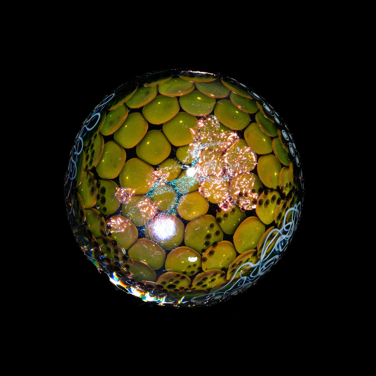Intricate yellow and green glass marble with pattern details on a black background