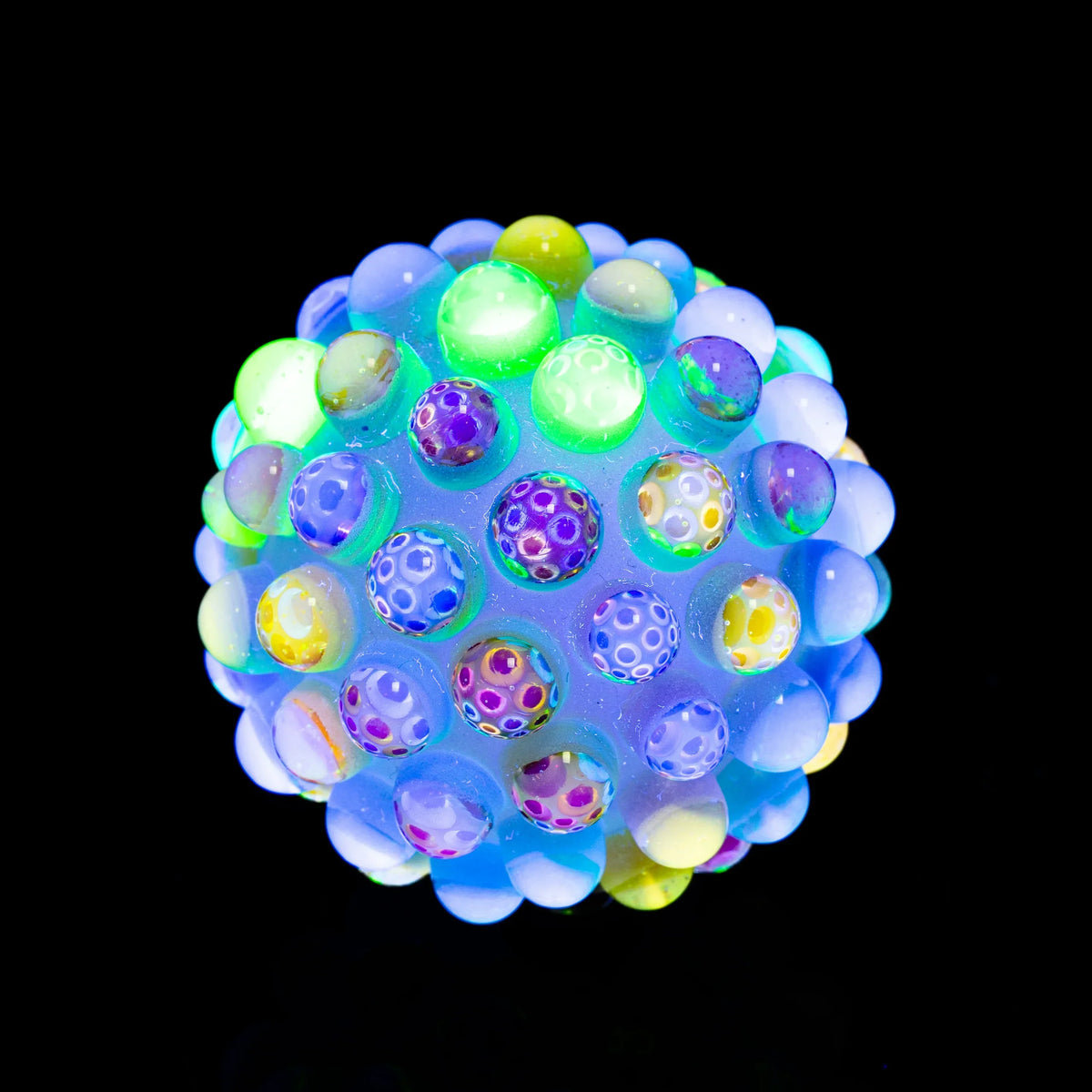 Colorful heady glass sphere with raised dots, glowing under blacklight on black background