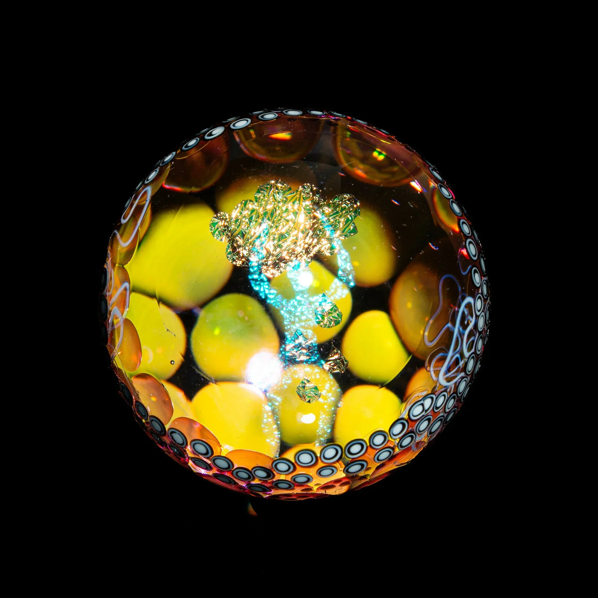 Colorful heady glass marble with intricate yellow, blue, and white designs on black background