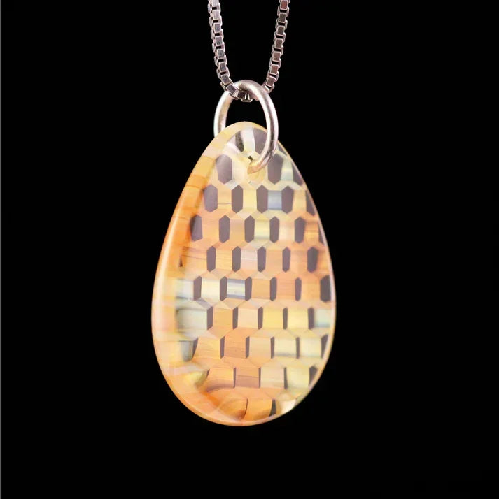 Teardrop glass pendant with geometric pattern on silver chain, black background