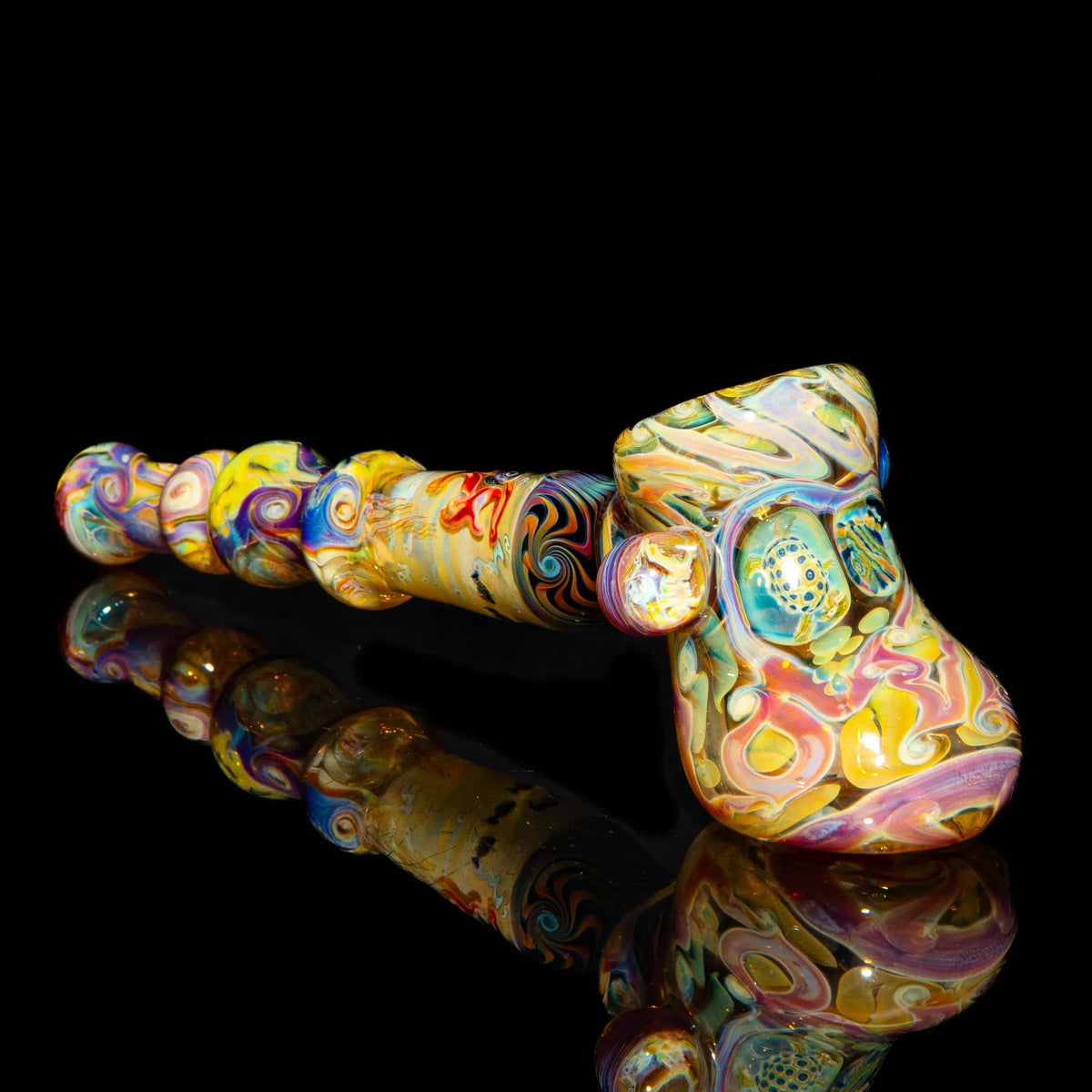 Colorful handblown glass pipe with intricate swirls, displayed on black reflective surface