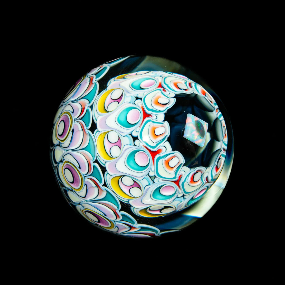 Colorful heady glass marble with intricate patterns and opal inclusion on black background