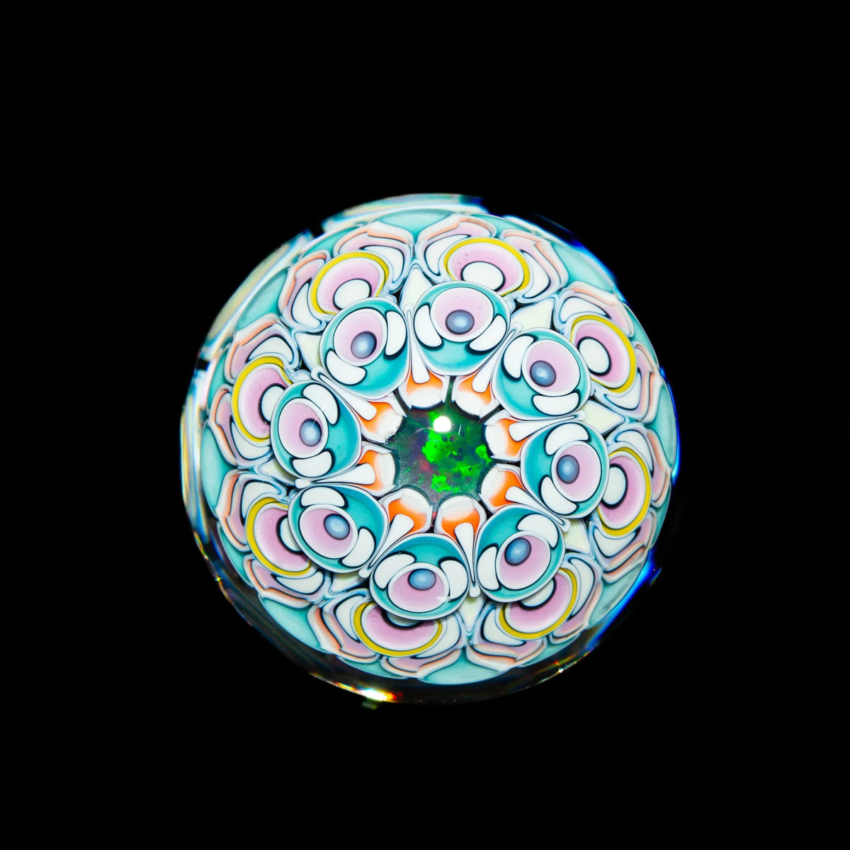 Intricate heady glass marble with colorful mandala pattern and green opal core on black background.
