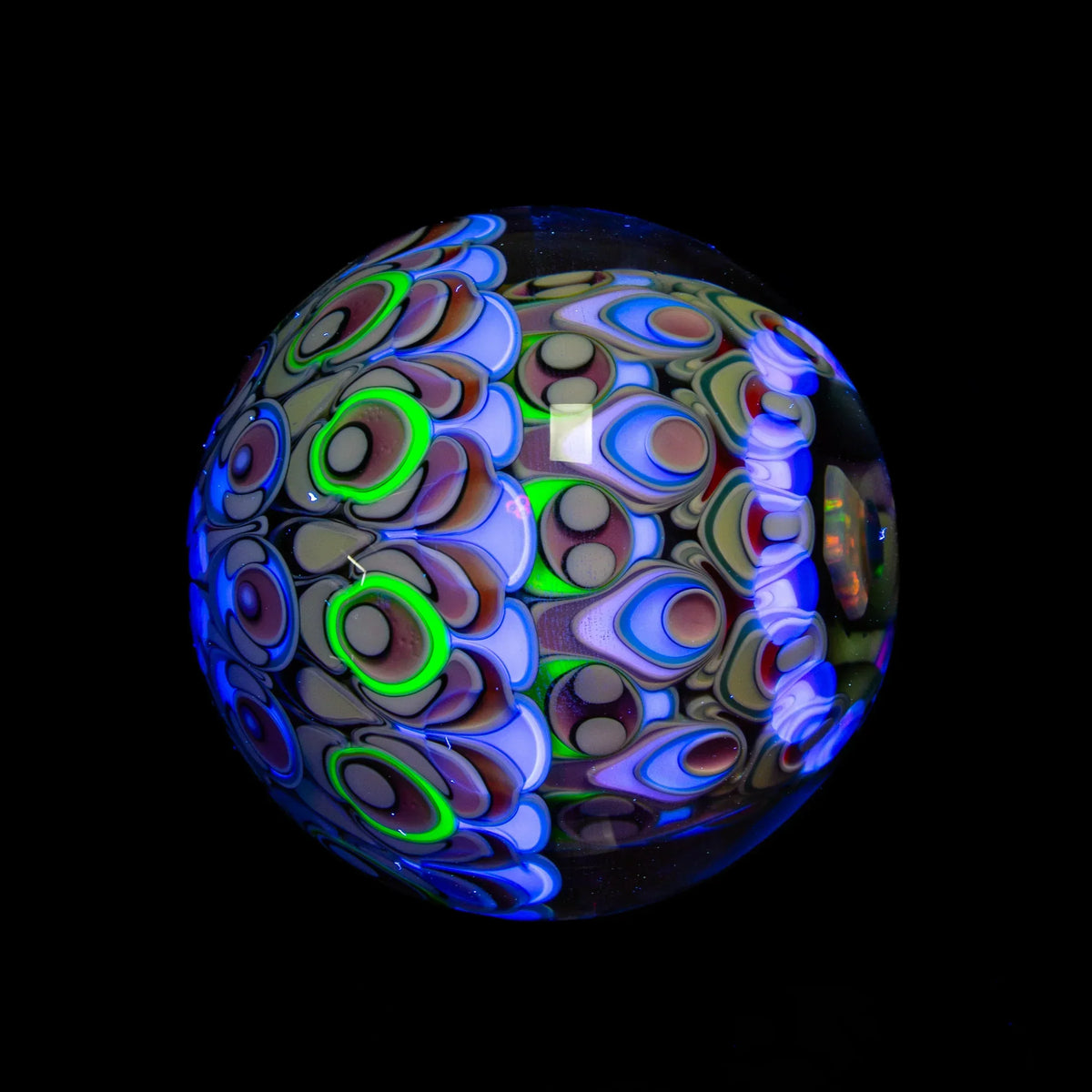 handblown glass marble with vibrant UV reactive patterns on black background