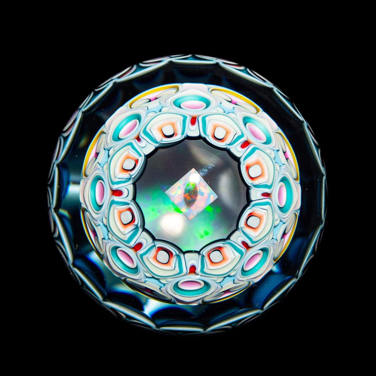 Intricate glass marble with colorful geometric patterns and opal inlay on black background
